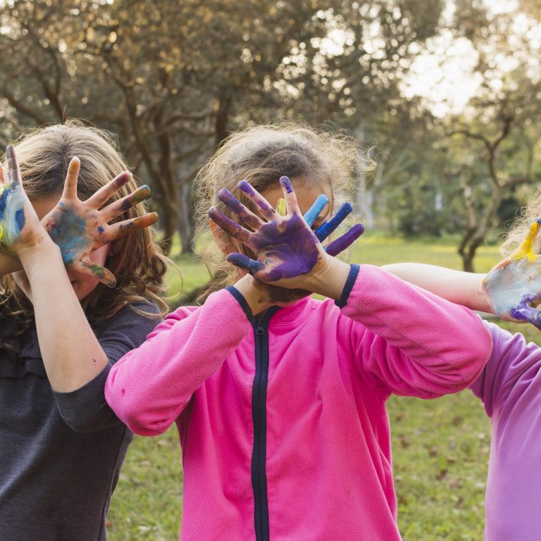 three-girls-covering-their-faces-with-painted-palms