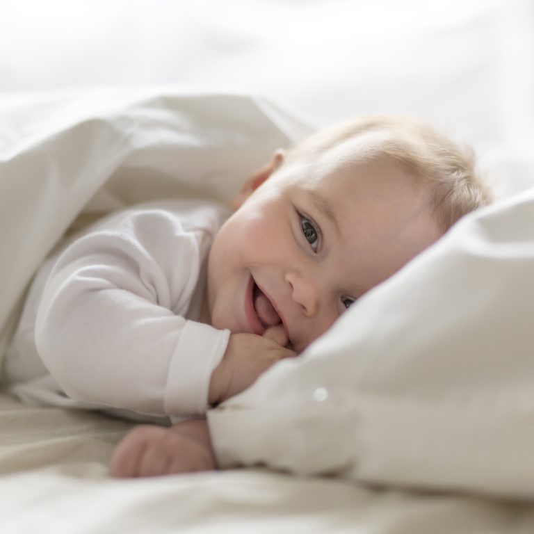 Cute happy 7 month baby girl in diaper lying and playing